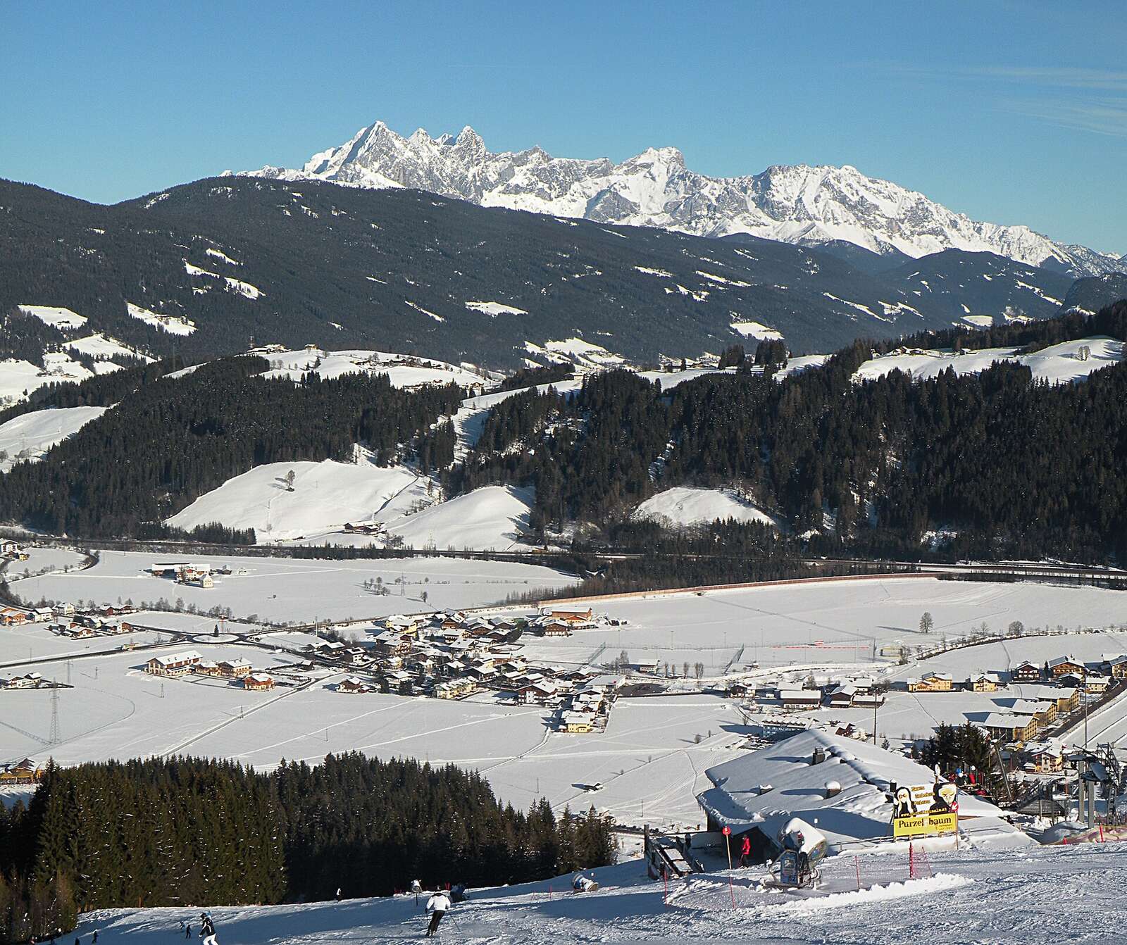 Dorp Flachau in een besneeuwde vallei met skipiste en bergen